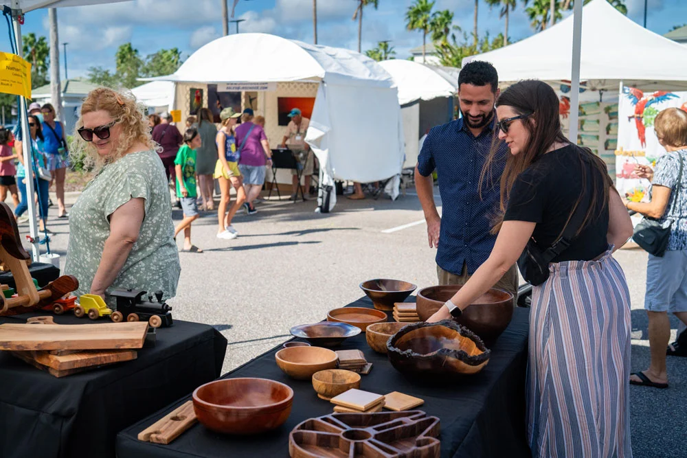 Visitors exploring handcrafted wooden bowls at the Space Coast Art Festival.